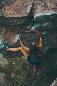 woman using a process to reach her goal of climbing a cliff