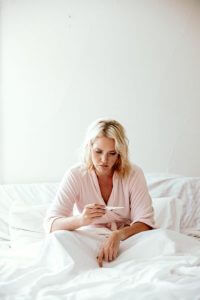 woman lying in bed checking her BBT to see if ovulation is happening for fertility