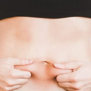 woman wanting to lose weight, holding her belly fat and struggling with weight loss