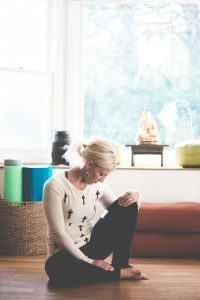 picture of a woman sitting on the floor, bent over because of symptoms of IBS