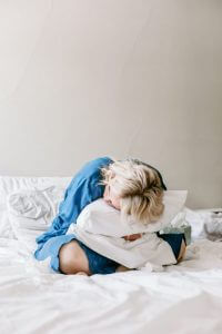a picture of a woman sitting doubled over with her period because it is so heavy wondering how to treat heavy periods
