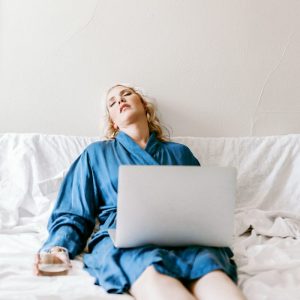 woman working on her laptop in bed looking so tired from fatigue