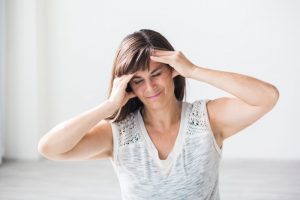 picture of a woman holding her head because she suffers from painful headaches and migraines