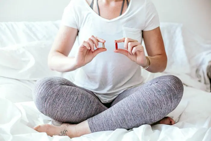 picture of a woman holding a capsule of vitamin D for fertility, hormone balance, PCOS, acne, hair loss, endometriosis thinking about vitamin D and hormone balance