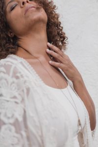 picture of a woman touching her neck while she is having a hot flash due to perimenopause and wondering how to treat perimenopause naturally