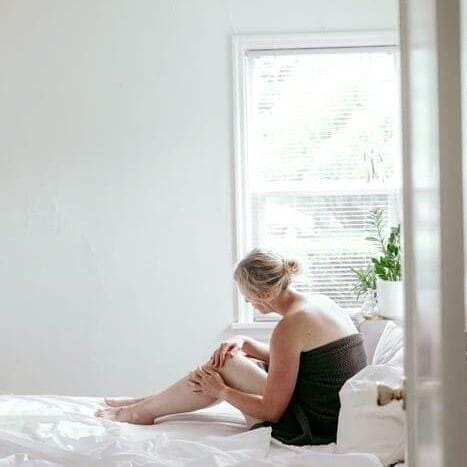 10 Common Misconceptions About Autoimmune Diseases Debunked picture of a woman lying on a bed holding her knee because it is painful due to rheumatoid arthritis