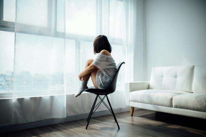 The Impact of Hormone Imbalance on Mental Health picture of a woman sitting on a chair looking out a window suffering from anxiety and depression due to hormone imbalance wondering how to balance hormones naturally because of the connection of hormones and mental health