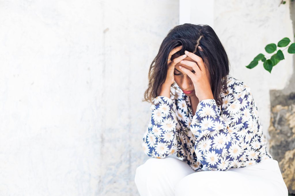 picture of a woman crouched down looking like she is in pain, due to PCOS and inflammation