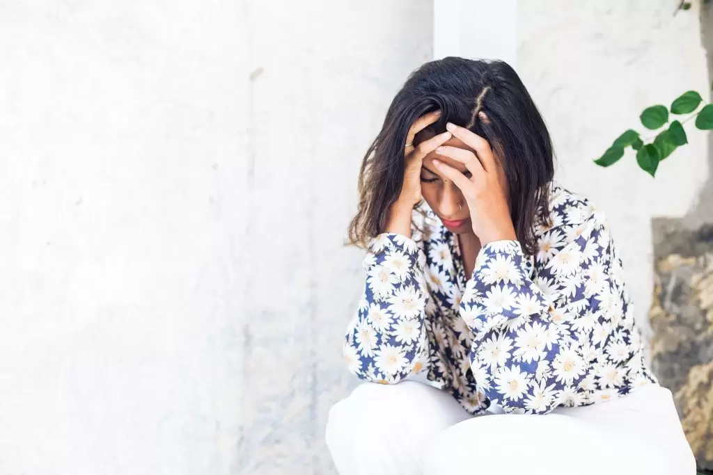 PCOS and Inflammation: What the Research is Telling Us picture of a woman crouched down looking like she is in pain, due to PCOS and inflammation