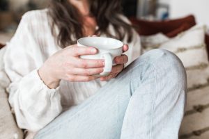 Best 5 Naturopathic Treatments for Women's Health (2025) picture of a woman on a couch sipping herbal tea and thinking about the Best 5 Naturopathic Treatments for Women's Health